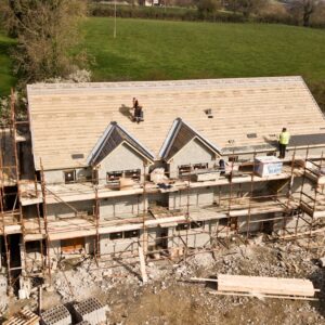 Aerial shot of a house under construction in Clonmel, Ireland. Workers on the roof.