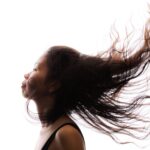 A high-contrast profile of a woman with her hair flowing, showcasing movement and expression.